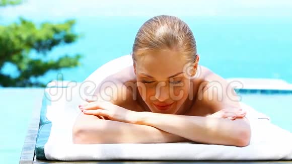 在游泳池旁边的温泉床上微笑的女人视频的预览图