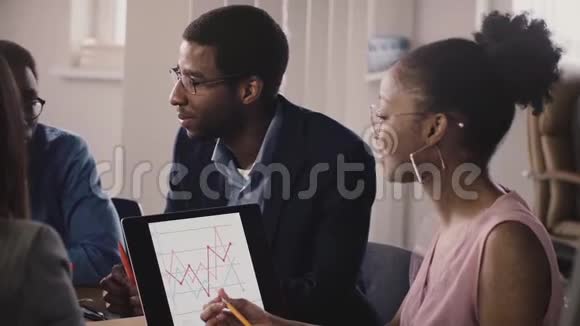 非裔美国人商务人士在办公室会议上交谈展示手势和交流看手提电脑图表视频的预览图