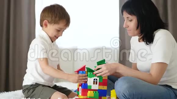 幸福的家庭母亲和儿子在家里的白色床上玩彩色积木视频的预览图