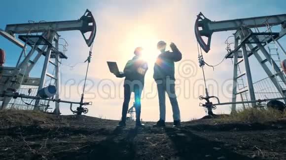 男性工程师站在燃料泵机之间说话能源石油天然气燃油抽油机视频的预览图