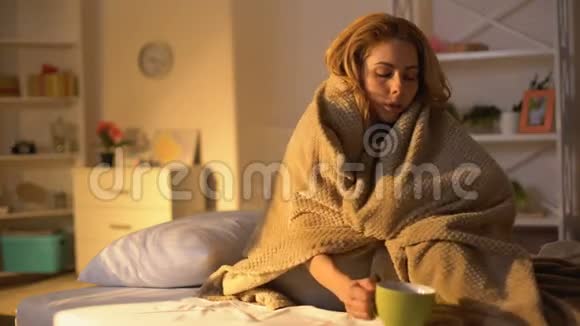 生病的女性躺在床上毯子上坐在床上喝热茶保健病毒视频的预览图