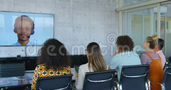 在现代化办公室举行视频会议的混合种族企业高管的后视图视频的预览图