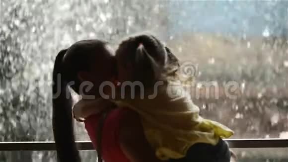 可爱的小女孩正在拥抱和亲吻她美丽的年轻妈妈母亲节快乐瀑布在背景上视频的预览图