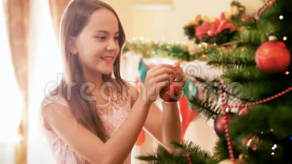美丽的微笑少女在家中的圣诞树上挂着五颜六色的宝布尔家庭装饰屋视频的预览图