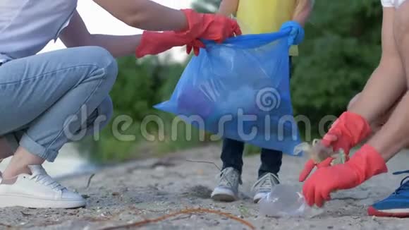 慈善清洁带着小孩子戴着橡胶手套的年轻家庭在肮脏的海滩上收集垃圾视频的预览图