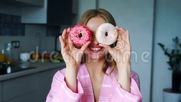 微笑的女孩用釉面甜甜圈遮住他的眼睛很漂亮的女人视频的预览图