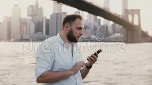 快乐成功的欧洲商人在智能手机上打电话在布鲁克林大桥4K附近交谈和微笑视频的预览图