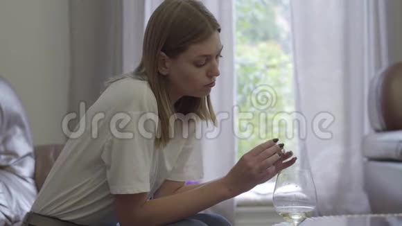 悲伤的女人拿着结婚戒指在酒杯下家庭问题背叛离婚分手的概念不安分的女孩视频的预览图