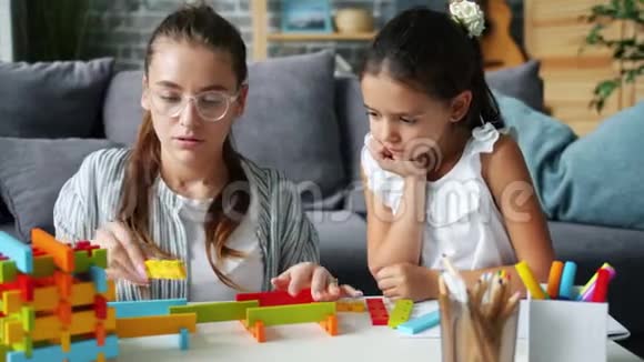 可爱的小女孩在家里和体贴的妈妈玩木玩具视频的预览图