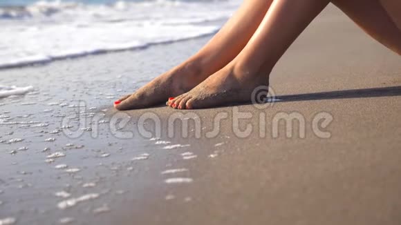 海水冲刷着晒黑的雌性脚女孩的腿躺在沙滩上夏天放松视频的预览图