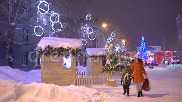 圣诞节购物圣诞节圣诞节的购物者晚上穿过繁忙的城市街道慢动作妈妈和她的儿子视频的预览图