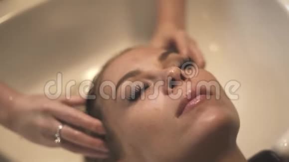 美丽的女性在水疗中心洗头的同时接受头部按摩视频的预览图
