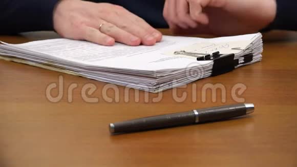 手把一叠文件移到桌上的钢笔上视频的预览图