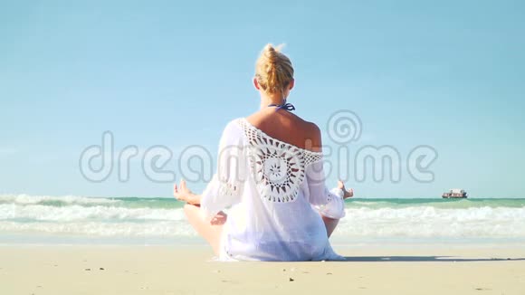年轻的金发女人在海滩上做瑜伽视频的预览图