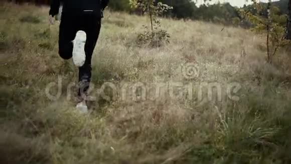 慢动作人在高大的草山上奔跑后视图追踪拍摄镜头跟随越野运动员跑视频的预览图