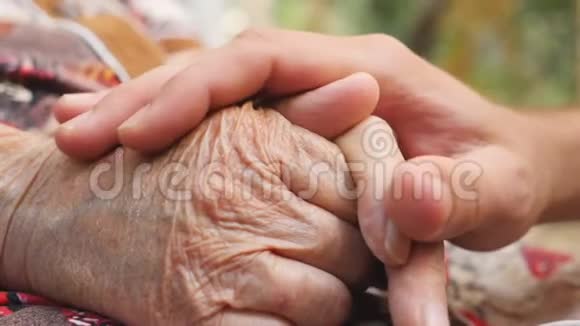 合上年轻的男性手安慰户外一位老妇人的老胳膊孙子和奶奶花时间视频的预览图