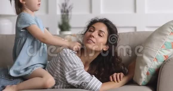 可爱有趣的孩子女儿挠痒亲吻妈妈在沙发上玩耍视频的预览图