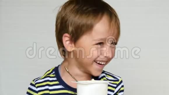 小男孩嘲笑照相机孩子坐在桌边吃酸奶快乐的情绪婴儿食品视频的预览图