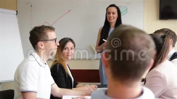 不同的员工和女性教练在企业业务培训研讨会上举手参与其中视频的预览图