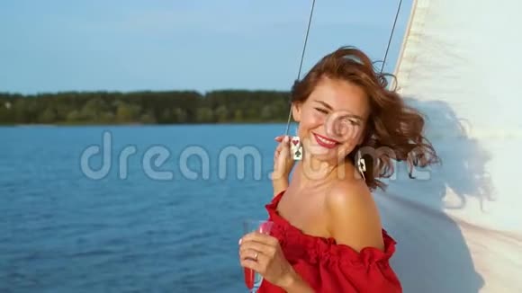 穿红裙子的漂亮女孩在帆船上放松和喝酒视频的预览图