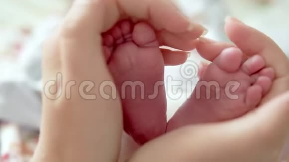 宝宝的脚在妈妈手里小新生婴儿脚在女性心脏整形的手特写妈妈和她的孩子快乐视频的预览图
