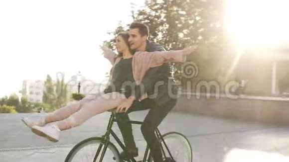 在户外活动中年轻夫妇骑在同一辆自行车上玩得很开心阳光下的背光也很快乐视频的预览图