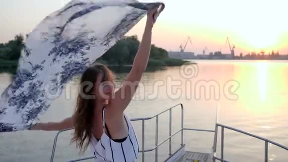 在夏日的夕阳下年轻女子站在帆船的船头视频的预览图