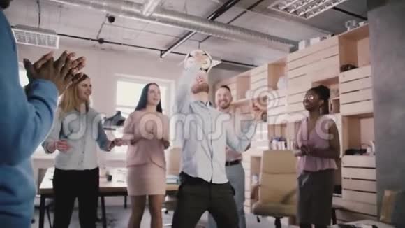 快乐的白人经理在头上踢足球性格开朗的多民族员工庆祝成功的办公室慢动作视频的预览图