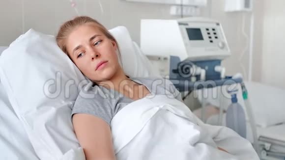 一位生病的年轻女子躺在病床上等待医生视频的预览图
