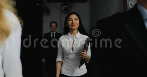 在亚洲女商人接电话的时候一商人在办公室里走动视频的预览图