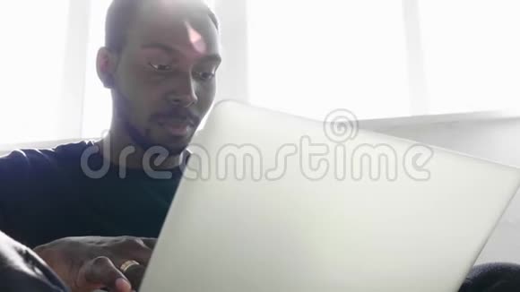 穿休闲服装的英俊的美国黑人商人正在使用电脑视频的预览图
