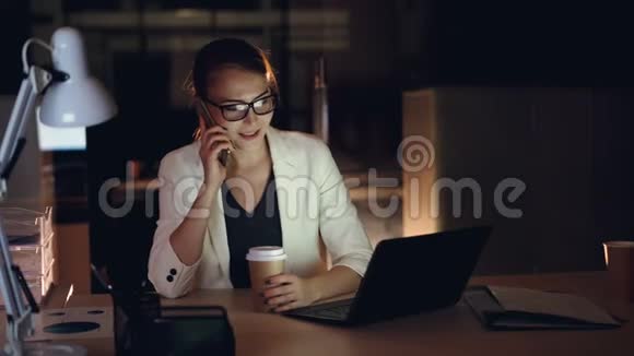 有魅力的女企业家正在用手机和笔记本电脑在深夜办公现代视频的预览图