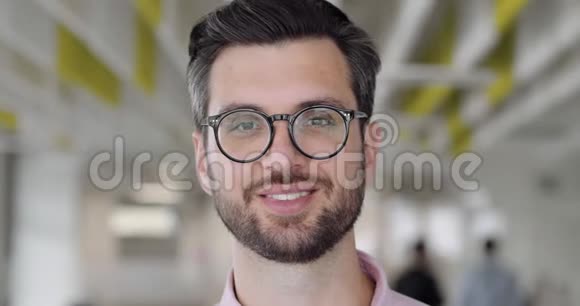 一个快乐的英俊男子在玻璃上看着镜头和微笑有胡子的男办公室工作人员心情好视频的预览图