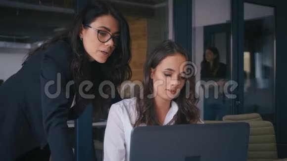 女组长对一名在办公室使用计算机的员工的项目进行修正两个自信的办公室视频的预览图