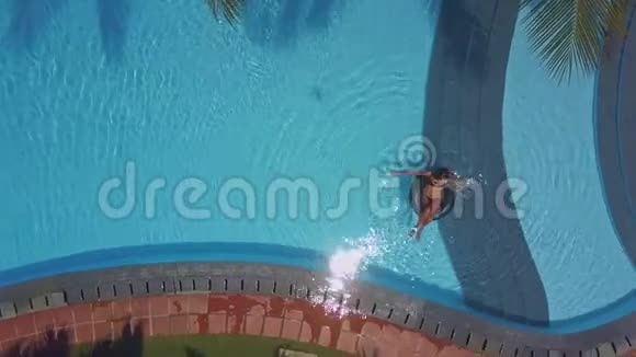 Flycam展示酒店游泳池女士坐在浮标上视频的预览图