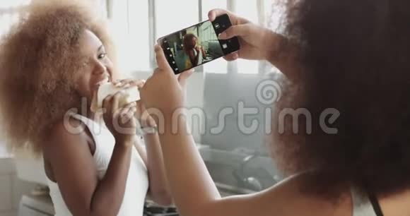 两个女人在为社交媒体拍照时玩得很开心在摆三明治时玩得很开心视频的预览图