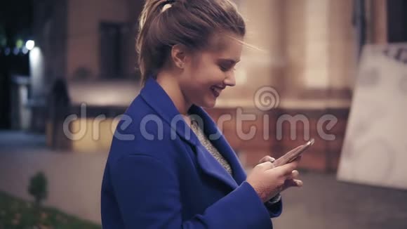美丽的年轻女子在城市深夜使用她的智能手机迷人的女孩发短信上网冲浪视频的预览图