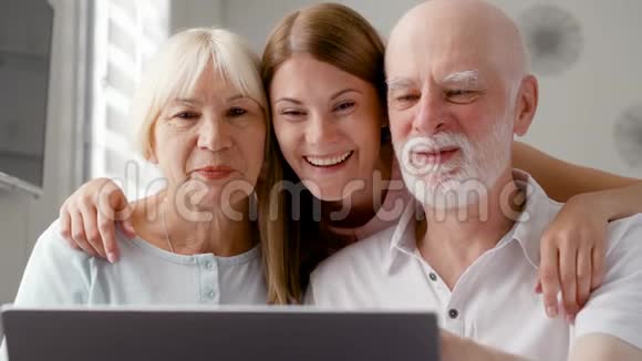 年长夫妇和他们的女儿坐在家里通过信使Skype聊天微笑着笑视频的预览图