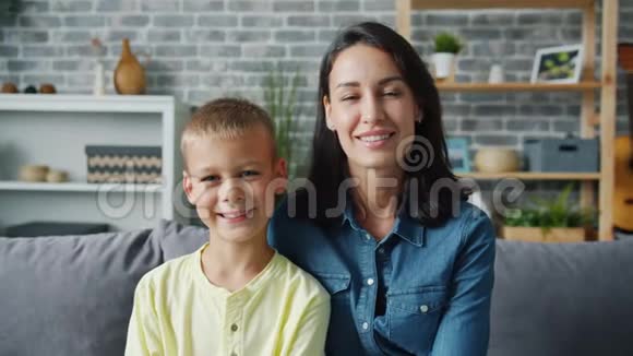 家庭幸福的母亲和儿子坐在室内微笑的画像视频的预览图