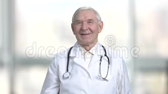 穿着白色外套和听诊器的资深老医生显示拇指向上视频的预览图