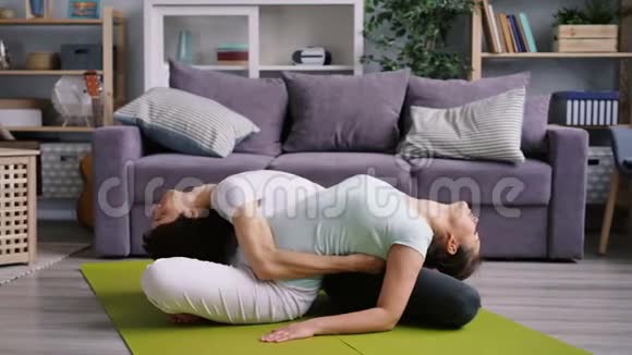 灵活的丈夫和妻子一起在家锻炼为夫妻做瑜伽视频的预览图