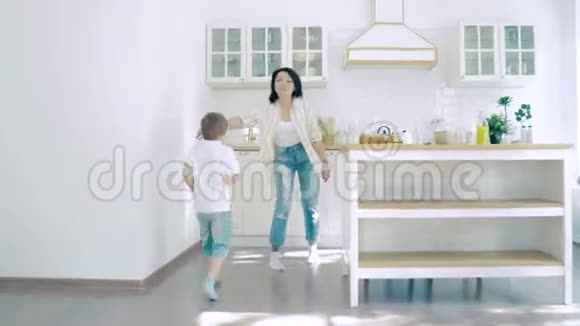 两个快乐的小男孩在厨房里跑去妈妈吃早餐视频的预览图