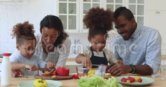 帮助父母切蔬菜沙拉的非洲小男孩和女孩视频的预览图