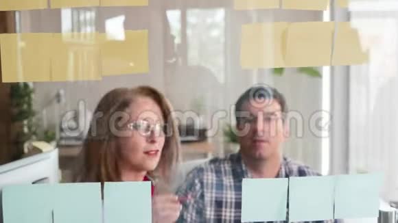 一群成功的人在玻璃门上分享他们粘糊糊的笔记上的伟大想法视频的预览图