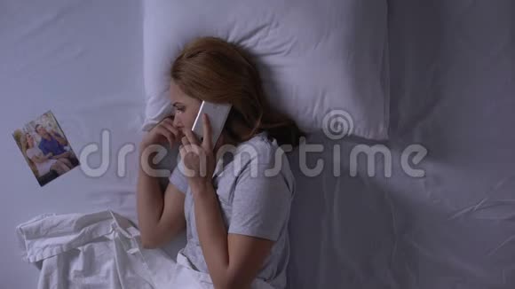 女人试图打电话给躺在床上看照片的男人背叛视频的预览图