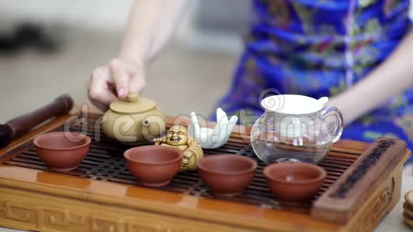 中国的茶道是一个穿着蓝色连衣裙的女孩用筛子把倒进水壶里视频的预览图