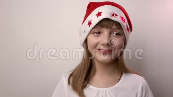 滑稽的白种人女孩戴着圣诞老人的帽子微笑在白色背景下笑视频的预览图