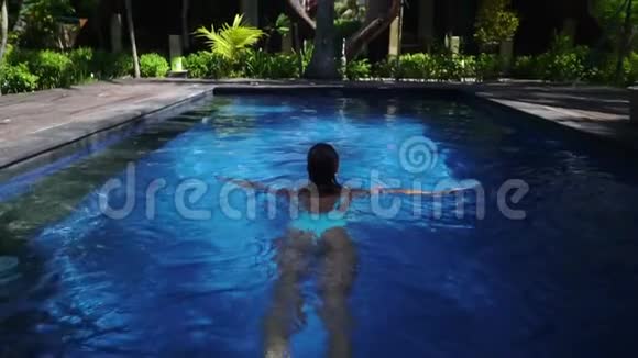 在美丽的游泳池丛林中游泳的女子室外镜头视频的预览图