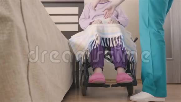 年轻护士照顾轮椅上的残疾老年妇女并将其转移到床上视频的预览图