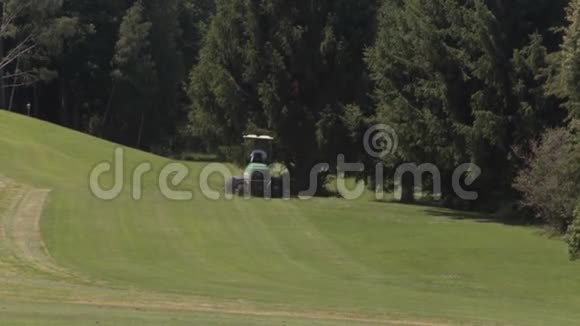 割草机在高尔夫球场边缘的草地上工作用大机器割草视频的预览图